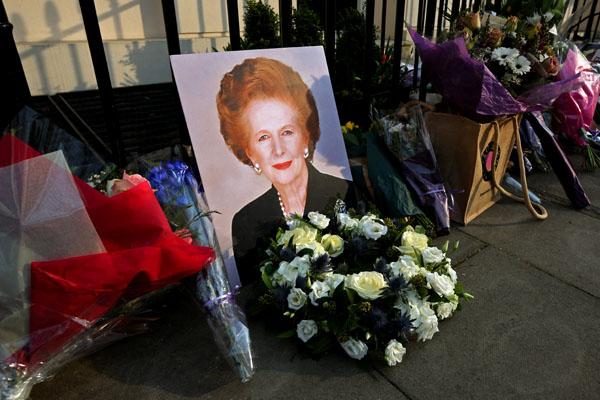 A portrait of former Prime Minister Margaret Thatcher is left next to floral tributes outside her residence in London.