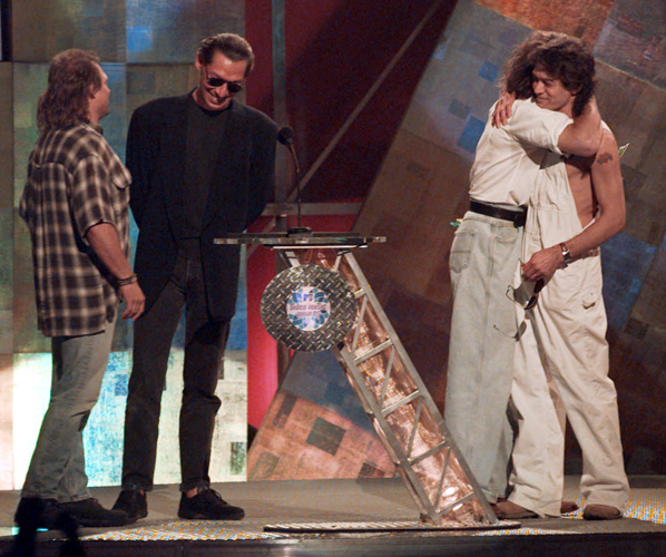 Former Van Halen bandmates David Lee Roth and Eddie Van Halen, right, embrace as they are reunited onstage at the MTV Video Music Awards in 1996. Bandmates Michael Anthony, left, and Alex Van Halen are also present.