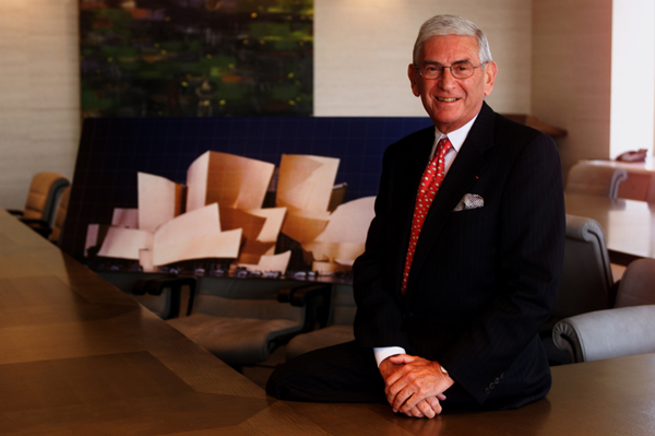 Eli Broad in 2000. Behind him is a photo of the Walt Disney Concert Hall design.