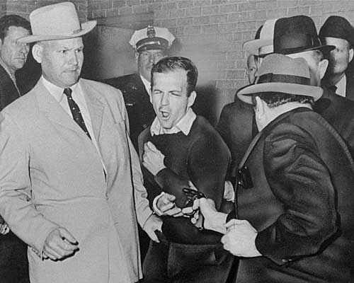 Plainclothesman Jim A. Leavelle, left, recoils as Jack Ruby shoots Oswald.
