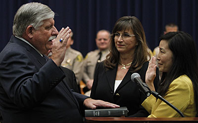 John L. Scott takes the oath of office, administered by Sachi Hamai, executive officer of the L.A. County Board of Supervisors. Alice Scott, center, watches as her husband is sworn in as Los Angeles County sheriff.