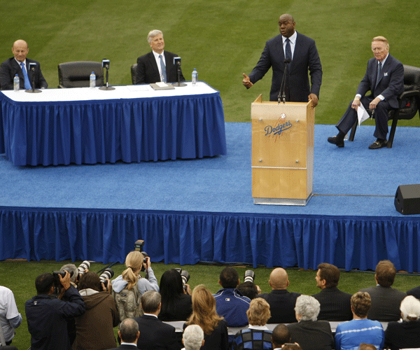 Scully, right, listens to Magic Johnson addressing the media during a news conference at Dodger Stadium.
