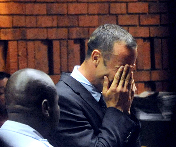 Pistorius hides his face in his hands during a bail hearing.
