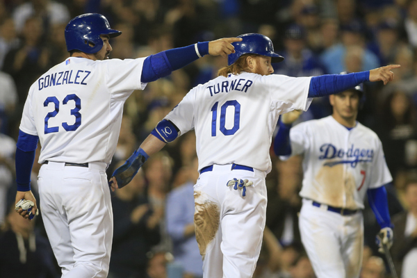 Dodgers first baseman Adrian Gonzalez, left, and third baseman Justin Turner point to Andre Ethier (not pictured) after he drove them in on a two-run double in the fourth inning against the Braves.