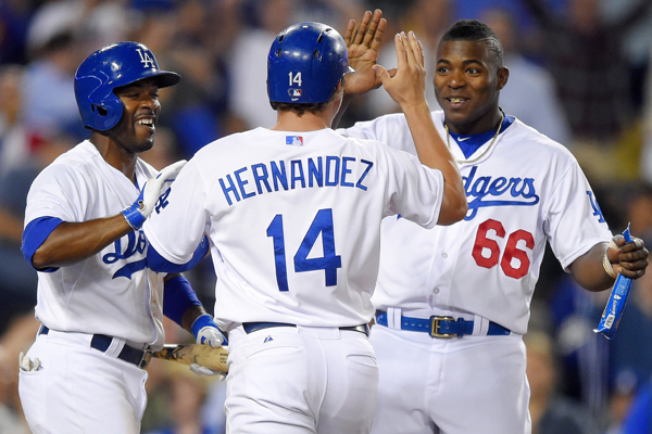 Dodgers' Enrique Hernandez, center, celebrates with teammates Yasiel Puig, right, and Jimmy Rollins after scoring the winning run on a balk in the ninth inning of a win over the Texas Rangers.