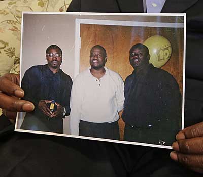 Anthony Scott holds a photo of himself, center, and his brothers Walter, left, and Rodney.