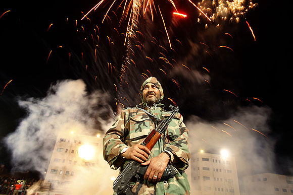 A member of the government security forces is on duty amid a fireworks display in Zawiya.