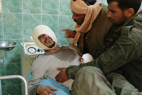 Rebel fighters comfort a wounded comrade at the hospital in Ajdabiya.