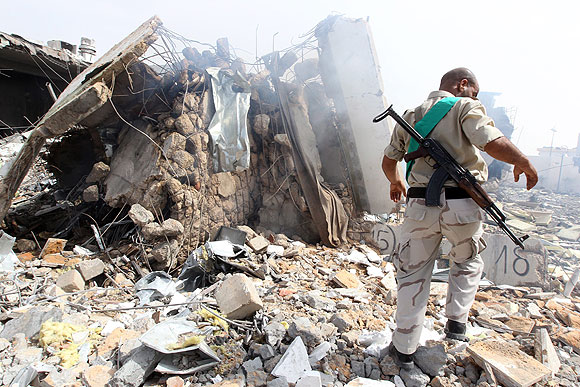 A Libyan soldier stands in a Tripoli compound belonging to Moammar Kadafi that was hit by NATO airstrikes.