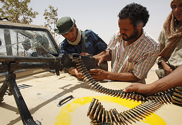 Rebel fighters try to fix a machine gun near the front line outside the village of Tiji in western Libya.