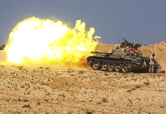 Anti-Kadafi fighters fire from tanks during clashes with loyalist forces near Surt.