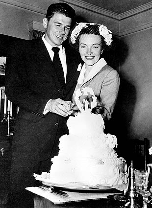 Newlyweds Ronald Reagan and Nancy Reagan cutting their wedding cake