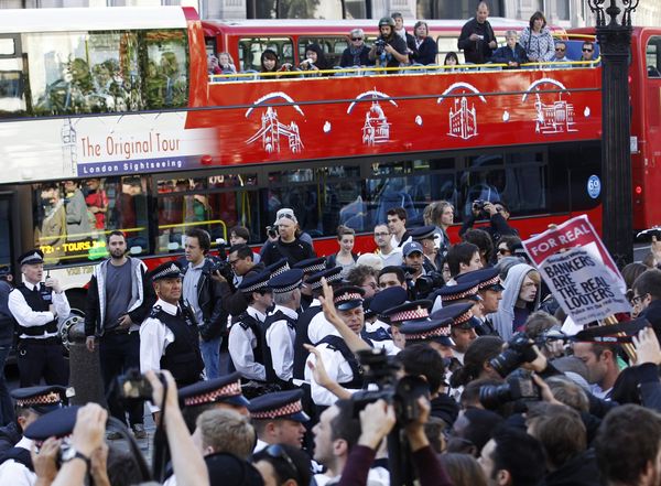A tourist bus passes demonstrators and police officers outside St. Paul
