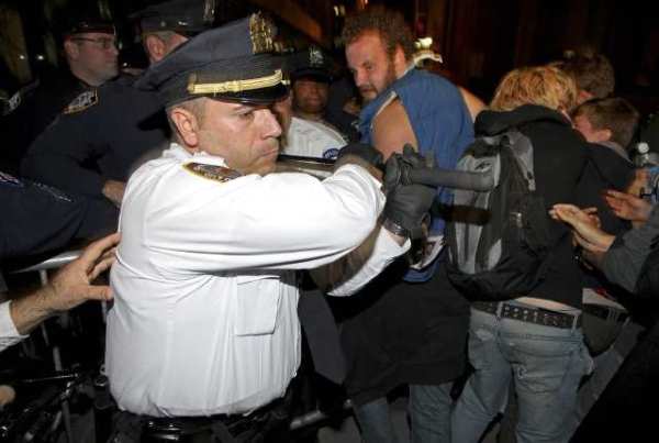 A police officer swings his baton to keep marchers behind barricades in Manhattan.