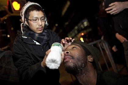 A protester pours liquid in the eyes of another protester who was pepper sprayed during a raid by New York City police.