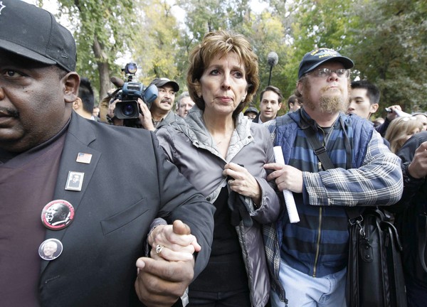 Linda Katehi is escorted from a small stage in the campus quad after she apologized to more than 1,000 students and faculty members.