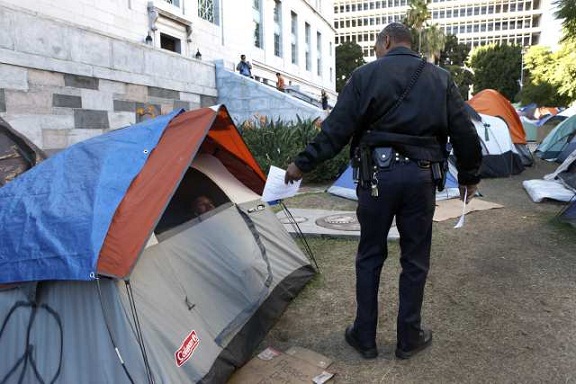 A general services officer hands out fliers letting Occupy L.A. campers know that they will no longer be allowed to stay overnight on the City Hall lawn. (Nov. 26, 2011)