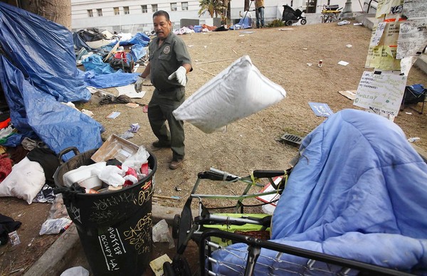 Sanitation worker Gino Ramirez starts clearing the debris left behind after the eviction of Occupy L.A. protesters. (Nov. 30, 2011)