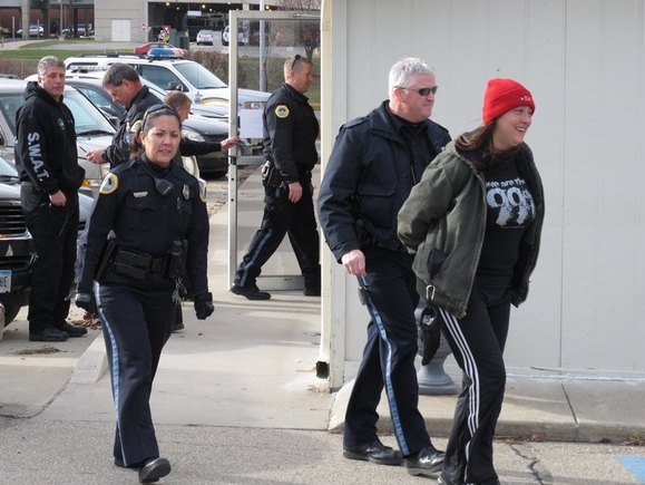 Julie Brown, 34, is escorted by police from the Iowa Democratic Party headquarters in Des Moines. (Dec. 19, 2011)