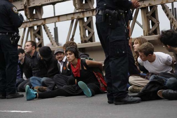 Protesters sit on the road in plastic handcuffs after being arrested on the Brooklyn Bridge.