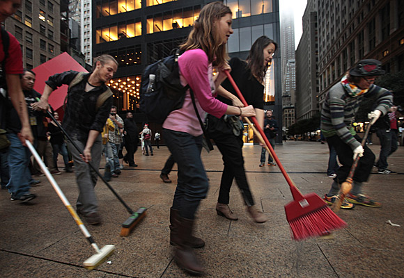 Protesters sweep the sidewalk in the financial district as part of a symbolic effort to clean up Wall Street.
