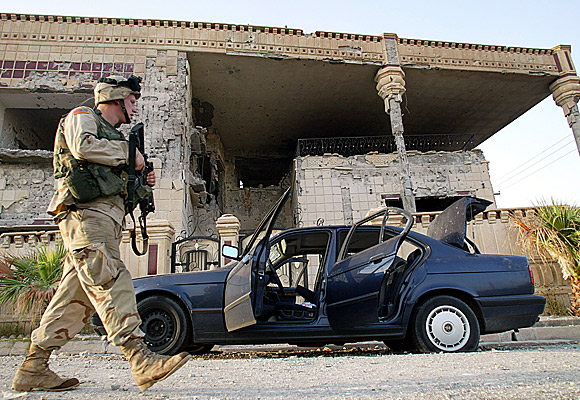 An American soldier stands guard outside the house in Mosul, Iraq, where Uday and Qusai Hussein were killed.