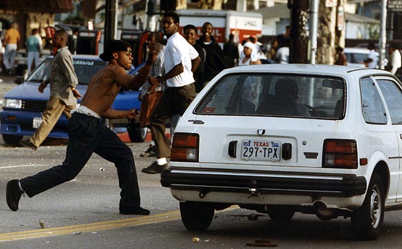 A rioter attacks a car on Florence and Normandie avenues. (April 29, 1992)