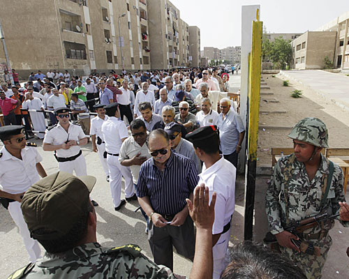 Egyptian army soldiers stand guard as hundreds of Egyptians line up outside a polling station in Cairo.