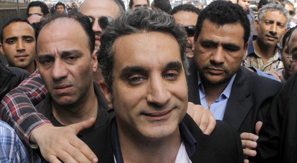A bodyguard secures popular Egyptian television satirist Bassem Youssef, who has come to be known as Egypt's Jon Stewart, as he enters Egypt's state prosecutors office to face accusations.