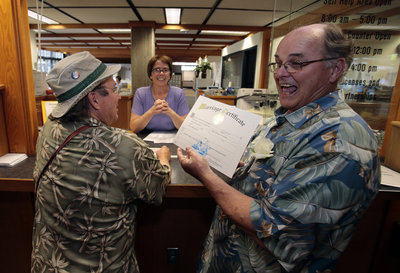 Bruce Carlson, right, shows off his ceremonial marriage license to wed his partner, Matt Friday, left, at the Lane County courthouse in Eugene, Ore.