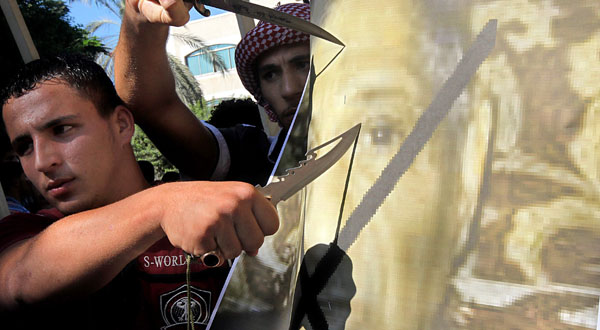 Palestinian muslims cut the poster of Morris Sadek, the Egyptian born Christian living in the US during a protest in front the UNSCO headquarters in Gaza City.