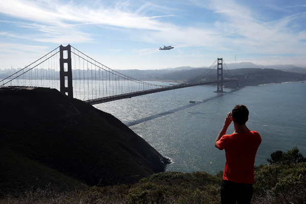 A spectator takes a photo of the Space Shuttle Endavour as it flies on top of a modified 747 jumbo jet over the Golden Gate Bridge while traveling to Los Angeles Friday in Sausalito.