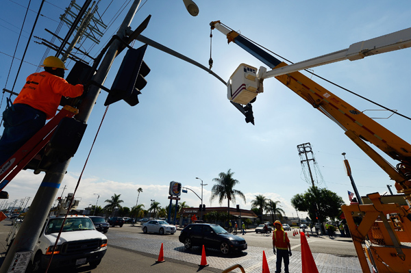 Workers prepare to bring down a street light temporarily to make room for the space shuttle Endeavour.