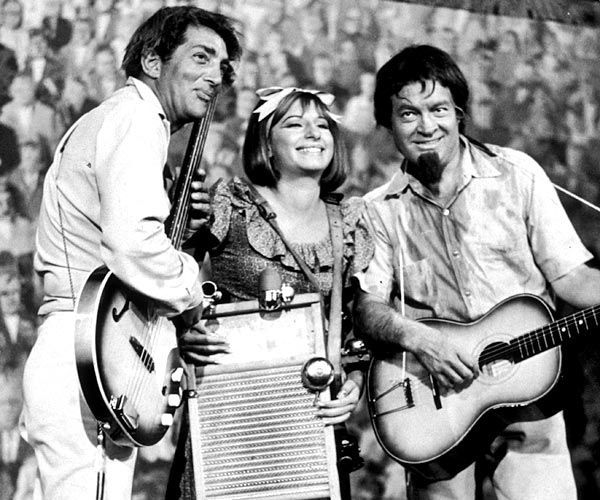Dean Martin, left, and Bob Hope play the guitar as Barbra Streisand plays a washboard and sings in a still from a television special in 1964.