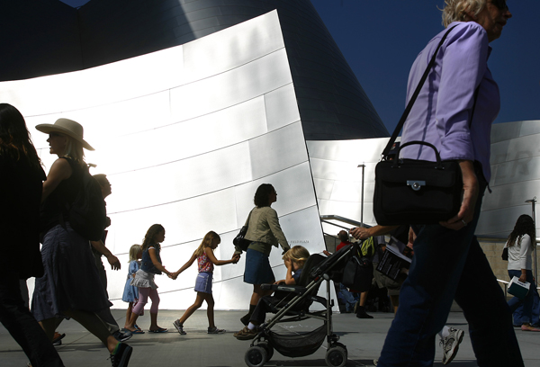 Pedestrians pass Walt Disney Concert Hall.