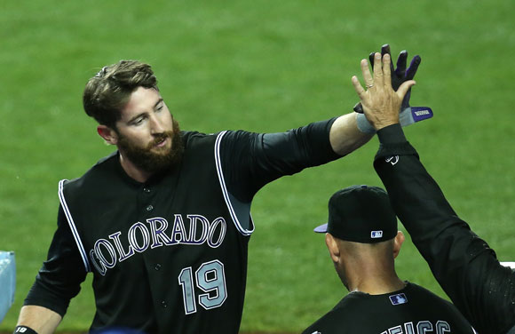 Charlie Blackmon is greeted by teammates after his run-scoring single in the 11th.