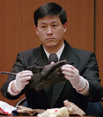 Los Angeles Police criminalist, Dennis Fung, holds the bloody glove. 