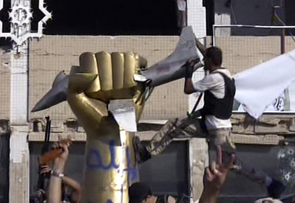 A rebel fighter climbs on a statue inside Moammar Kadafi's compound in Tripoli.