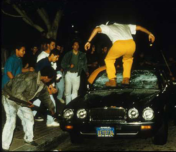 A mob attacks a car on the first night of 1992 riots.