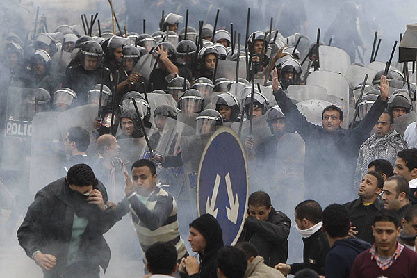 Protesters flee riot police amid plumes of tear gas in Cairo.