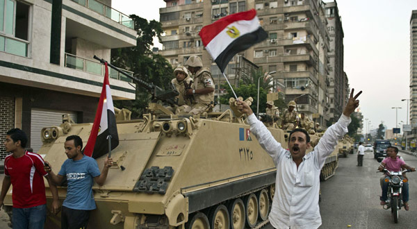 Egyptians salute Army tanks upon their deployment on a street leading to Cairo University.
