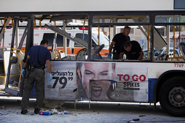 Police officers examine a bus targeted in a bombing in Tel Aviv.
