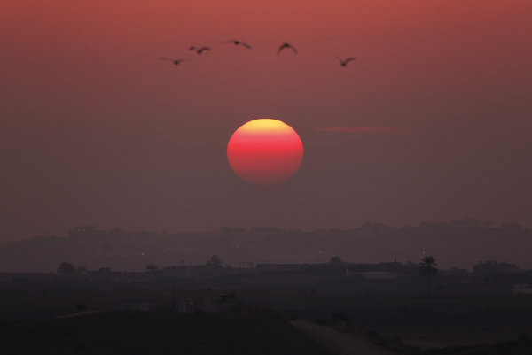 The sun sets over the central Gaza strip, as seen from a hill at the Israeli town of Sderot.