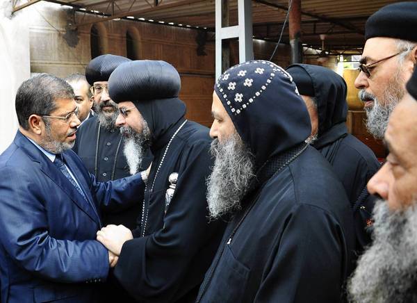 Egypt's Islamist president, Mohamed Morsi, left, receives condolences from Coptic Christian priests at his sister's funeral in Sharqiya. Fighting between Israel and Hamas has put Morsi's government in the spotlight. 